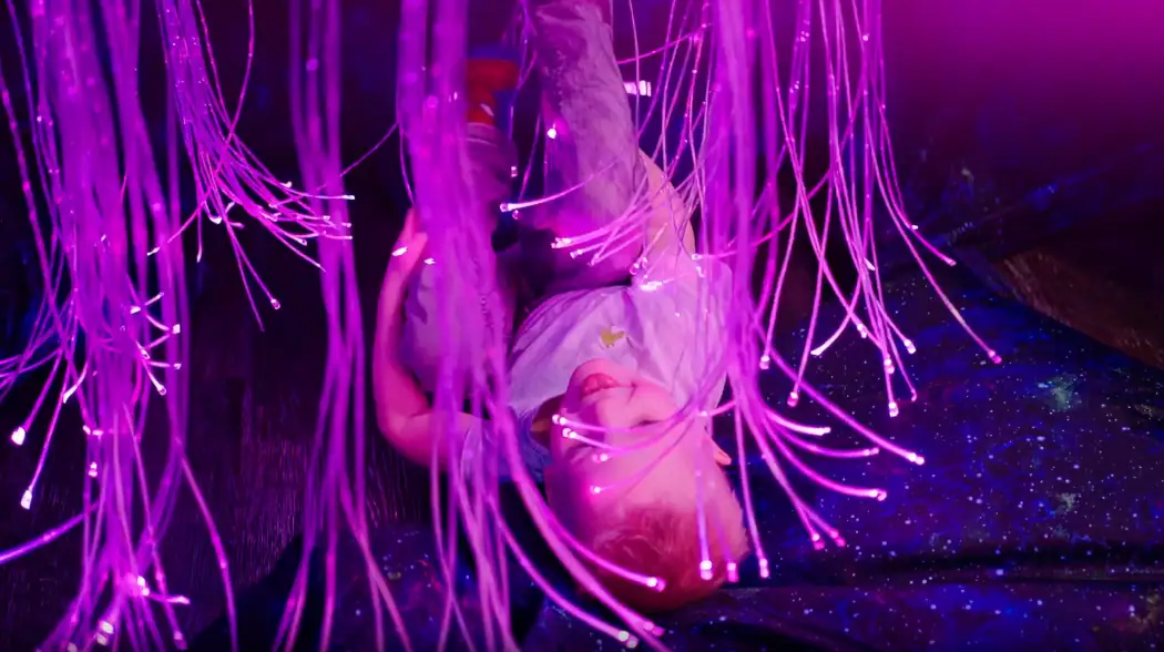 Child playing with fiber optic sensory lights in colorful play area