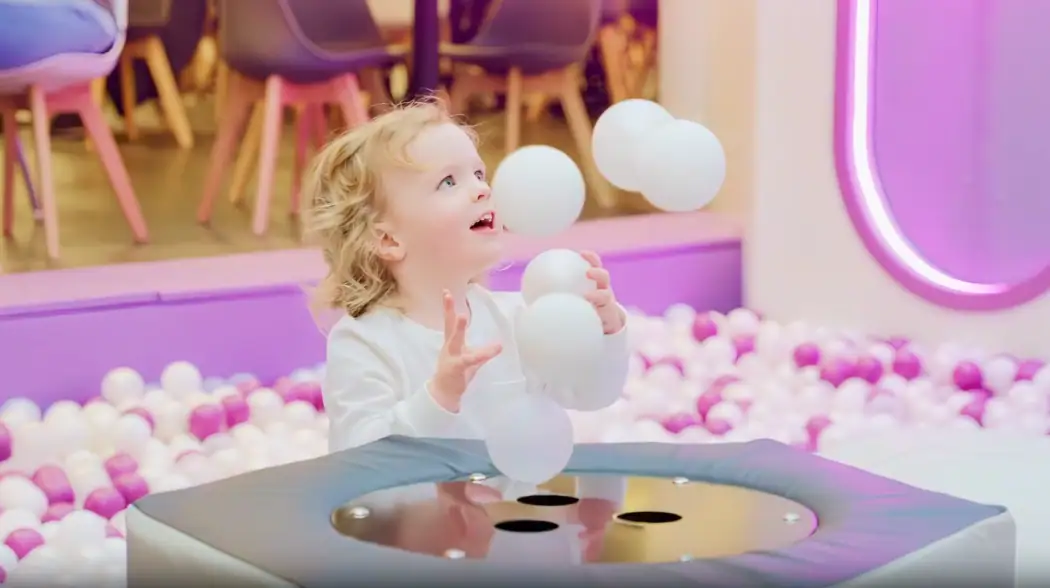 Toddler playing with giant balls at an interactive sensory play table
