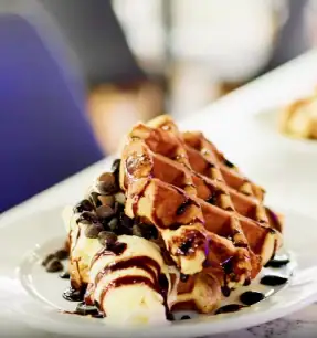 Dessert waffle with banana and chocolate sauce in family cafe