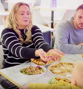 Family dining with parent and children enjoying meal in indoor play cafe