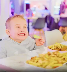 Happy child eating fries at Little Astronauts indoor play centre cafe