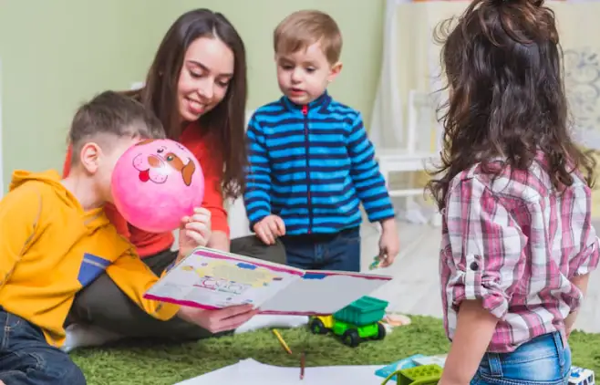Nursery children learning with teacher reading book and playing indoors
