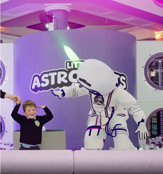 Astronaut mascot playing with child in indoor soft play activity area