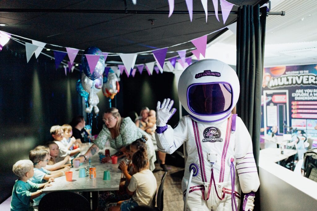 Children at a birthday party table at Little Astronauts in Hull, with Cosmo the astronaut waving