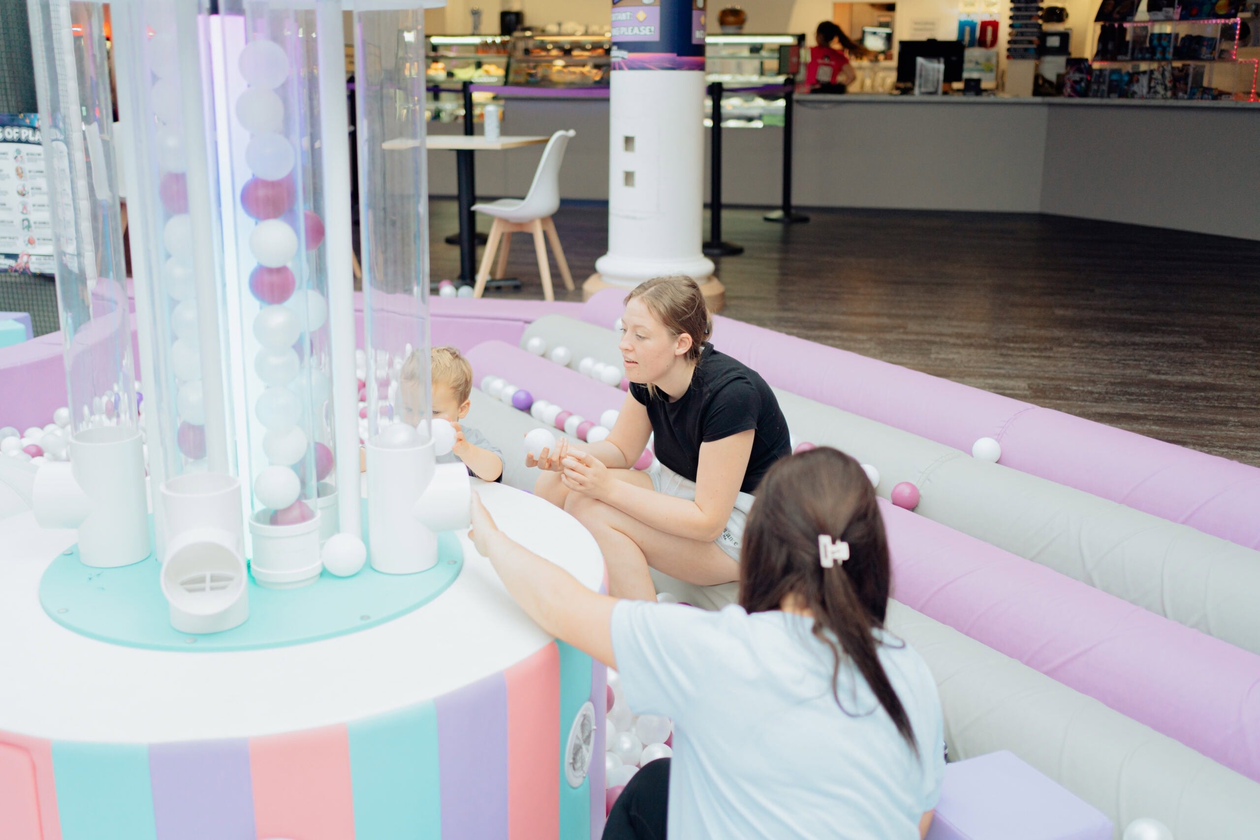 Family friendly indoor play area with parents and children enjoying ball activities