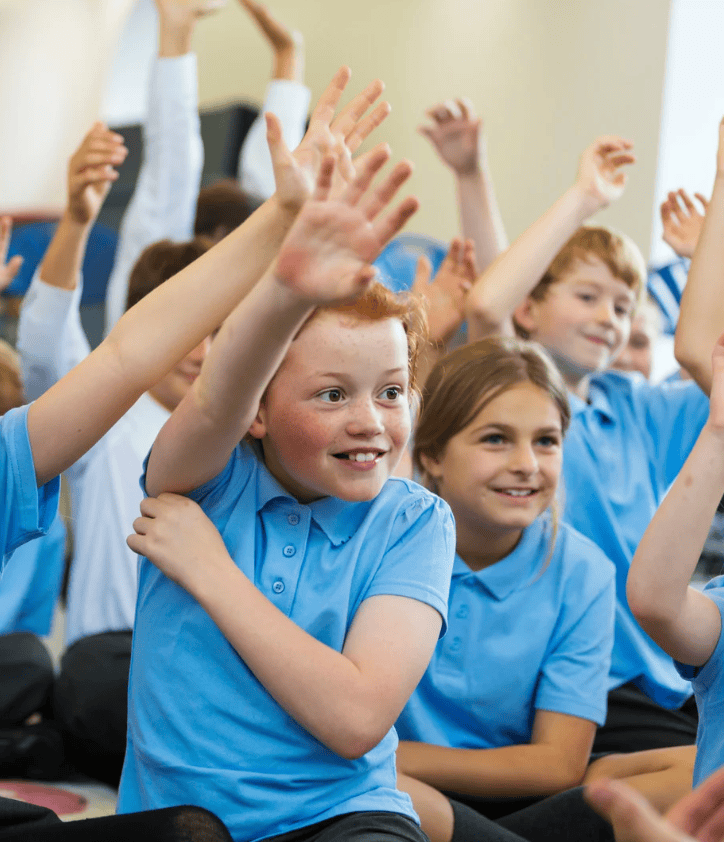 School group children participating in interactive learning activity raising hands