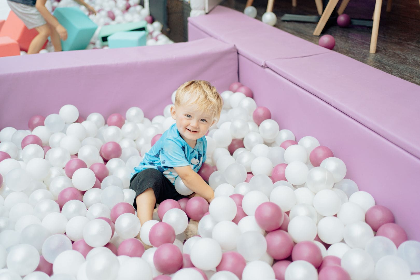 Toddler playing happily in compressed giant ball pool indoor soft play area