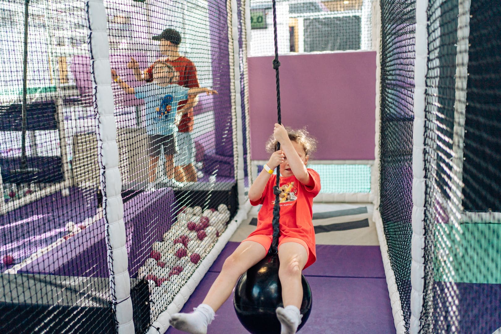 Over 4s play zone child using rope swing in indoor soft play area