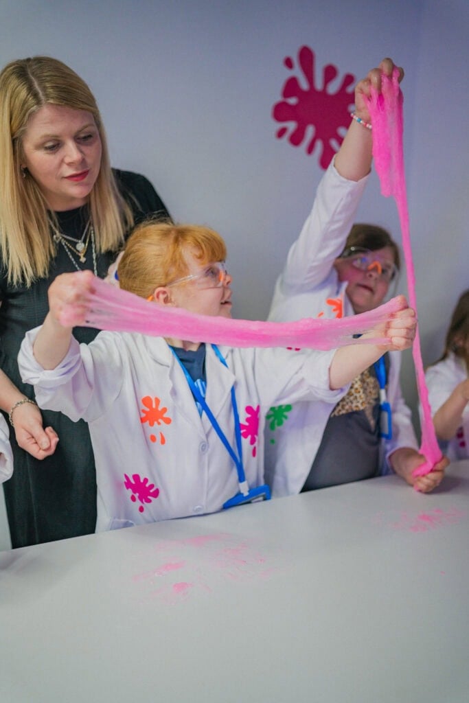 A child stretching pink slime at Planet Gloop