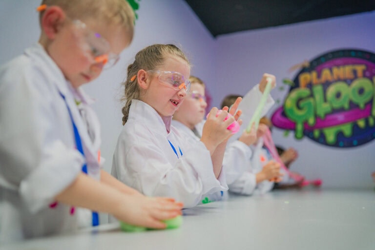 Children at the slime lab benches at Planet Gloop